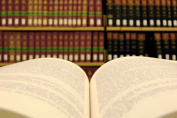 Open book shown in front of a bookshelf