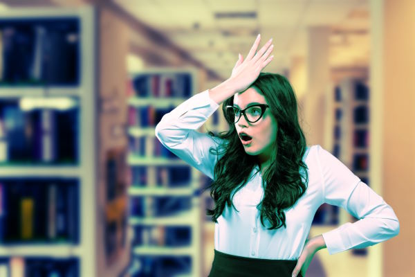 Librarian in a library with her palm on her forehead